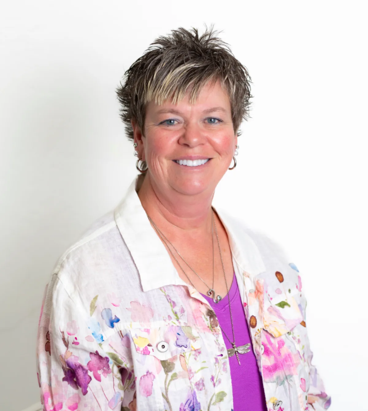 Woman in a floral linen jacket smiling against a white studio background