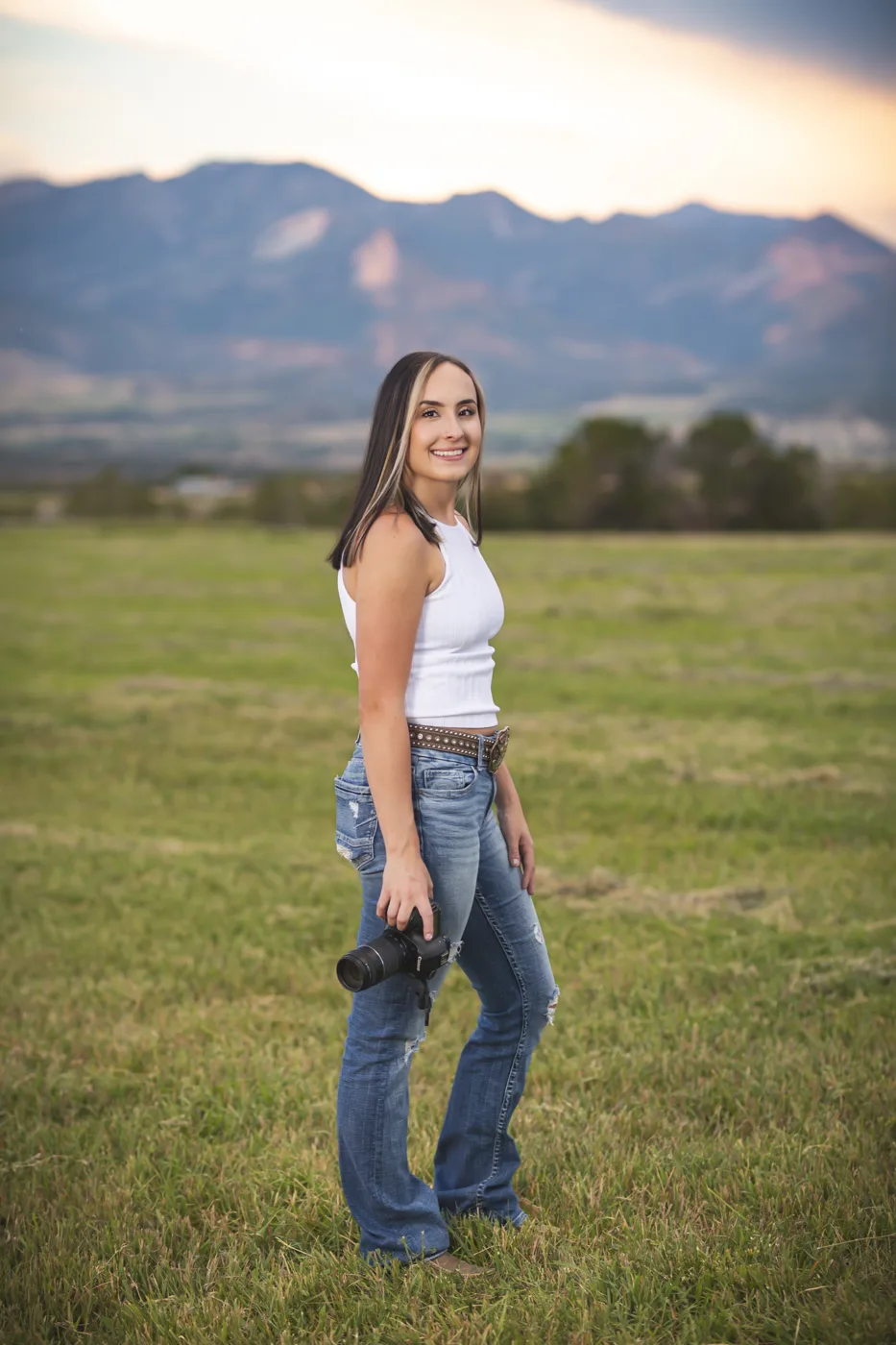 Cory Gallegos, owner and photographer of Cory Lynn Photography LLC, holding her camera in a Colorado field